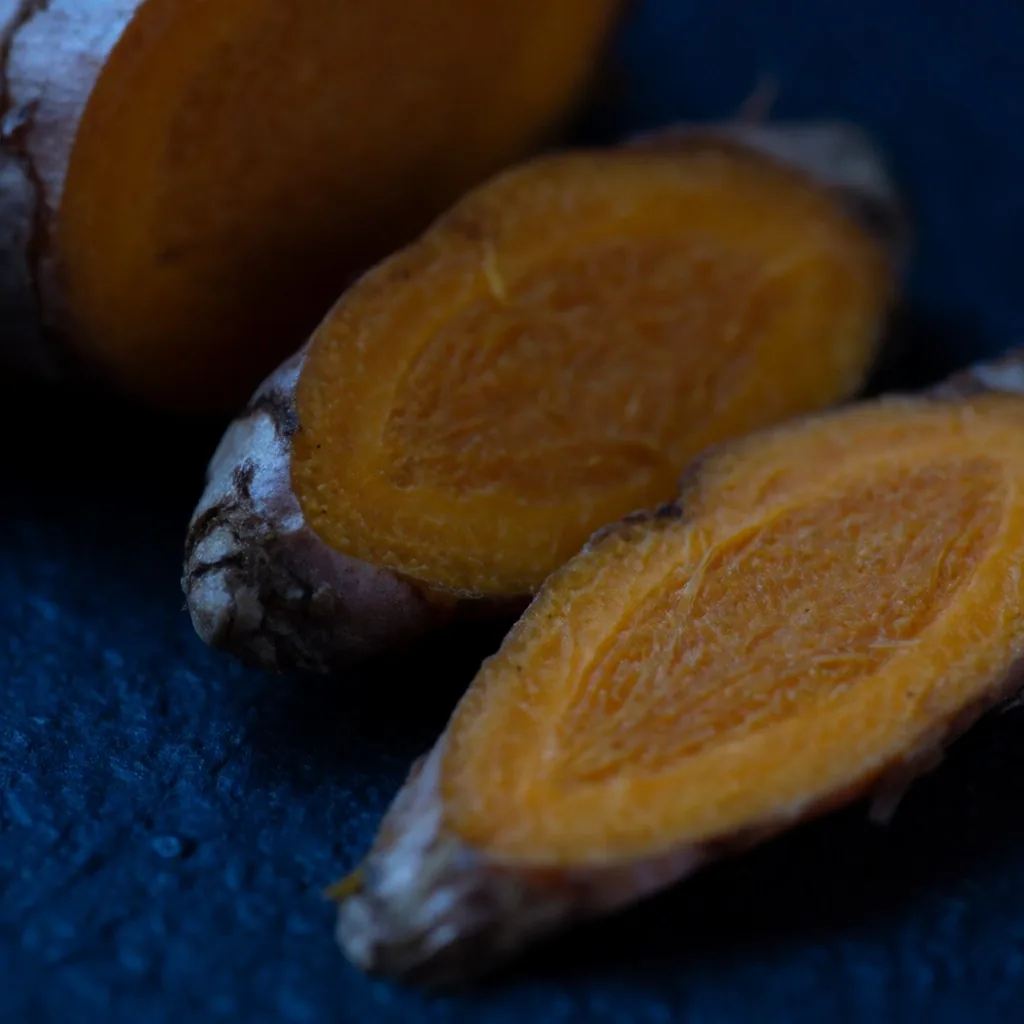 Close-up of fresh turmeric root on a dark surface